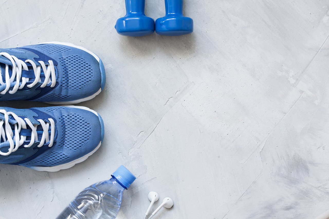 flat lay sport shoes bottle of water dumbbells and earphones